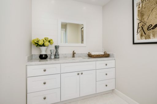 A spacious white bathroom with mirror, counter, and flowers