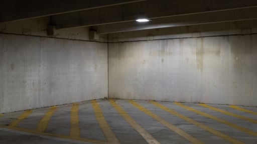 A creepy parking area with shabby walls and yellow stripes on the floor