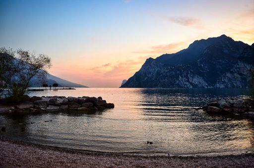 landscape photo - evening view from the beach bay to the south garda lake with mountains, cliffs, sunset