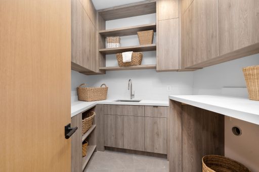 A small laundry room with beige furniture and white floor.