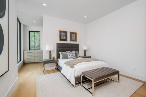 A spacious bedroom featuring a large bed next to a wall lamp.