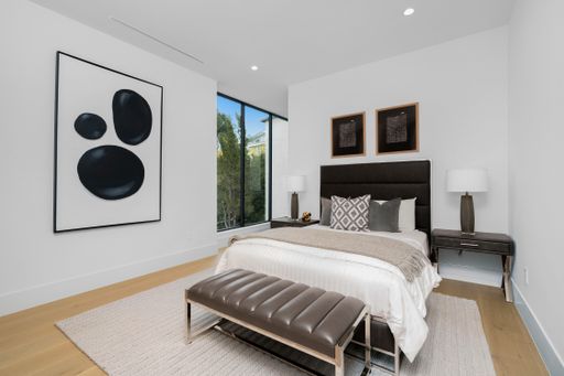 A spacious white bedroom with abundant natural light and a large bed.