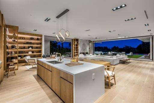 A spacious kitchen with wooden floors, a large white island, and abundant natural light.