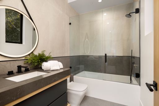 A bathroom interior with sink, toilet, and shower.