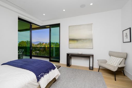 A spacious bedroom with large bed and city view balcony.