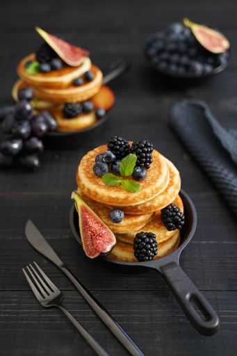 Indulgent Pancakes and Fresh Berries, as a cozy brunch against a black wood background.