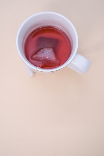 A vertical shot of a white cup with tea isolated on a light background