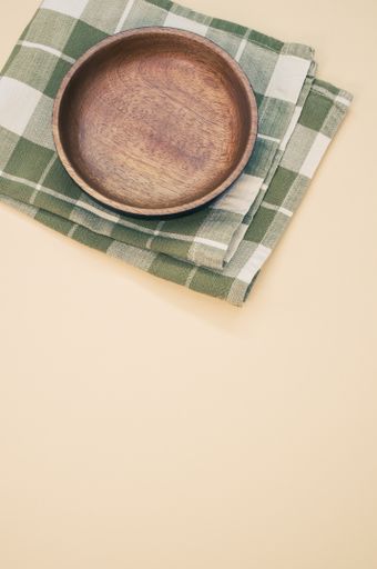 A vertical shot of a wooden plate on a green cloth isolated on a light background