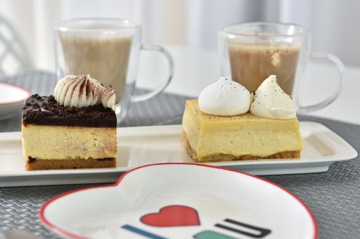 A selective focus shot of two pieces of cake and cups of coffee in a cafe