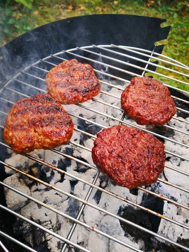 A closeup of meatballs cooking on a grill