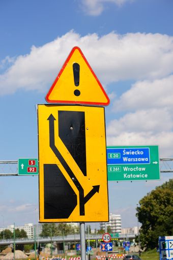 A vertical shot of yellow road warning signs on a blue sky background