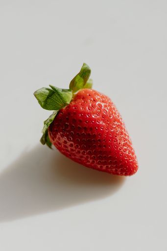 A fresh strawberry with leaf on a white table