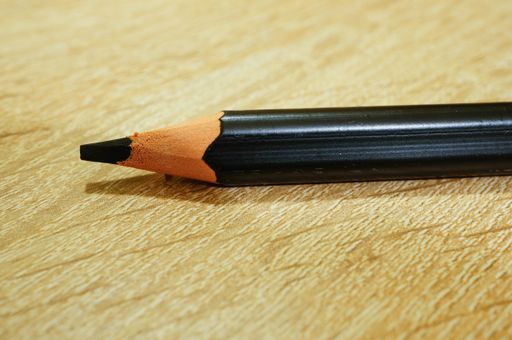 A closeup shot of a black drawing pencil on a wooden surface