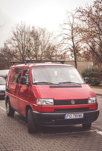 Parked red Volkswagen Transporter van on a parking spot.