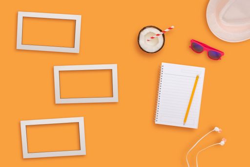 A top view of white blank frames with notebook on a light orange surface.