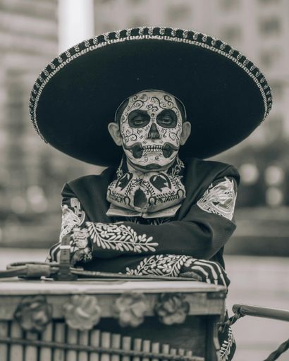 A monochrome shot of a sad man in a Day of the Dead outfit