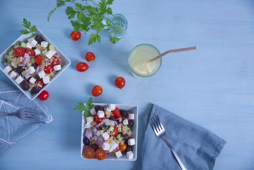 Greek salad in square plates, top view with cherry tomatoes, lemonade, on a light blue background.