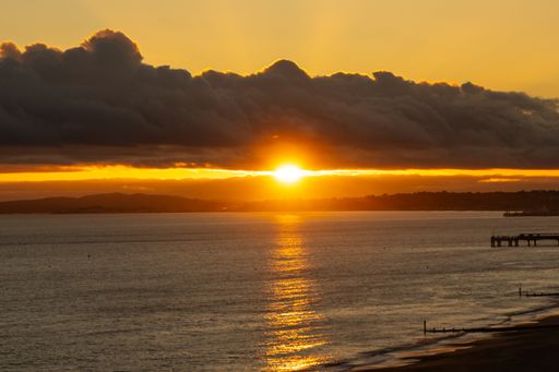 A sunset reflected in ocean water and clouds in Bournemouth