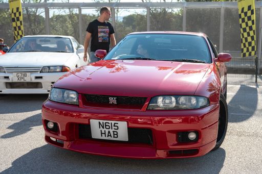 Front view of a red ninth-generation Nissan Skyline GT-R33 at a Japanese sports car meet.