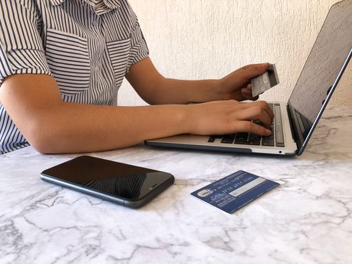 A person is working on a laptop and using credit cards for online payments