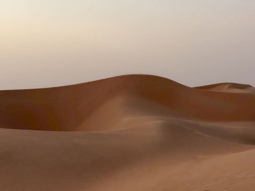 The sandy desert dunes with the cloudy hazy sky in the background