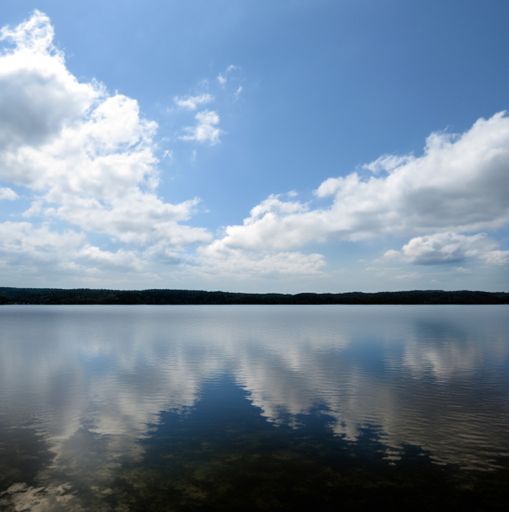 The serene waters of Lake Conroe reflecting the blue sky with white fluffy clouds