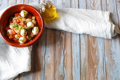 A top view shot of a salad made of vegetables and egg in a ceramic bowl on a wooden table