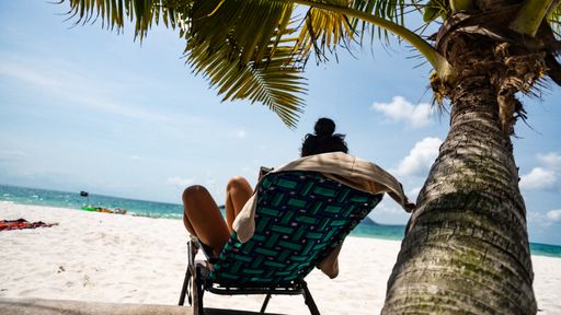 A girl reading book at the beach on tropical island having her holiday time and relaxing