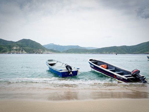 Two small boats on beach with mountains in background