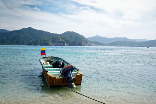 Boat on water by shore with mountains under cloudy sky