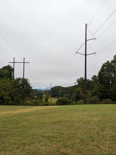 Utility towers in a field surrounded by trees and bushes in the Blue Ridge Mountains