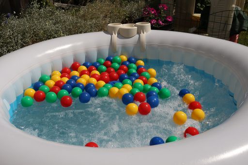 The multicolored balls float in the bubbling water of an inflatable pool.