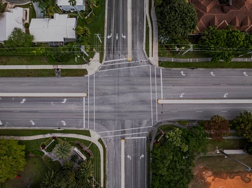 A top down view directly over a four-way intersection on a sunny day in Florida, with no cars or people in view