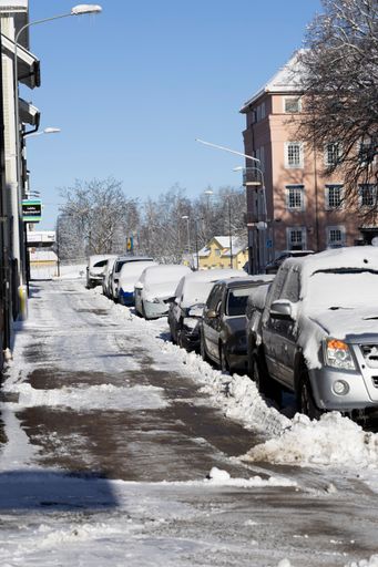 snow-covered cars on the road near the shopping center