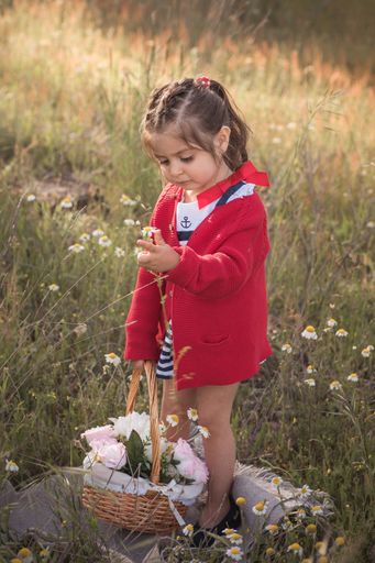 A little girl with flower basket in a field with blurred grass in the background