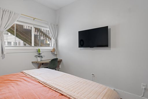 A bedroom featuring a wall-mounted flat screen TV above a cozy bed