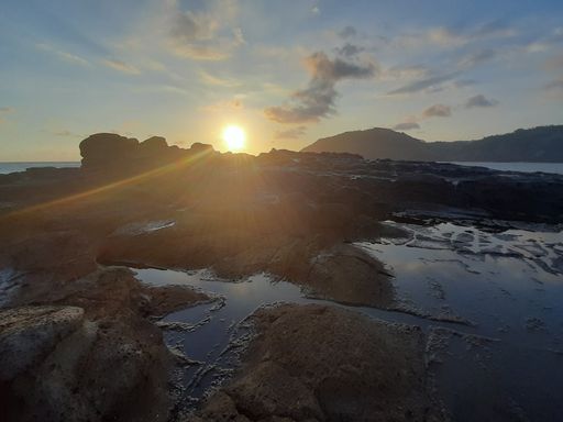 Beautiful sunbeam on extreme terrain from a rocky coast with a rock plateau and water puddles filled from waves at Wediombo beach, Java, Indonesia