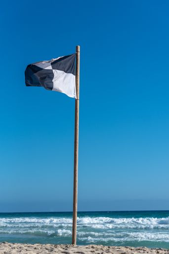 A vertical shot of a checkered black and white flag on the island of Formentera in Spain