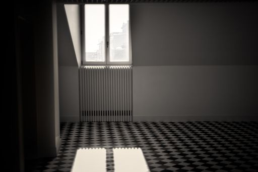 A monochrome tiled floor with a window in an empty room