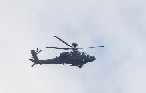 Military helicopter soaring through fluffy clouds in the sky