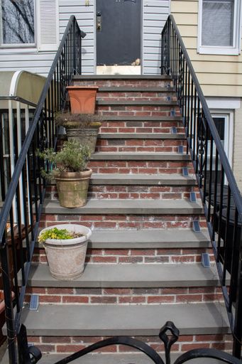 A pathway to a home with flower-filled planters