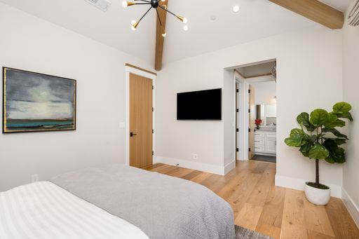 Bedroom with wall-mounted TV and wooden floor