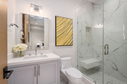 Bathroom with marble counter top, white fixtures, and marble accents