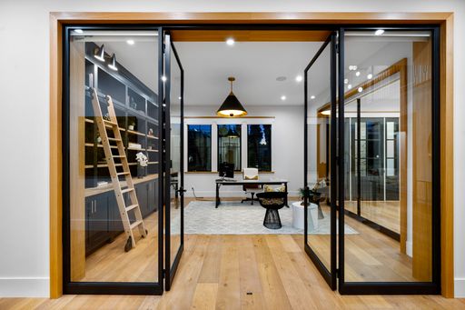 A room with expansive glass doors opening to a table in another area