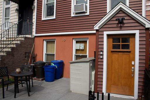 A red house with two white windows and a front door outside