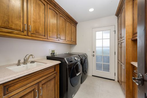 A laundry room with open cabinet doors, washer, and dryer in Encino, California