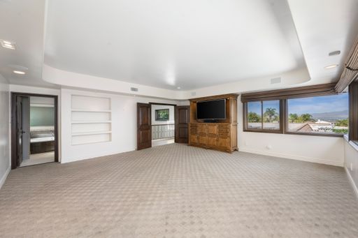 An empty room with ocean view through large windows, carpeted floor in Encino, California