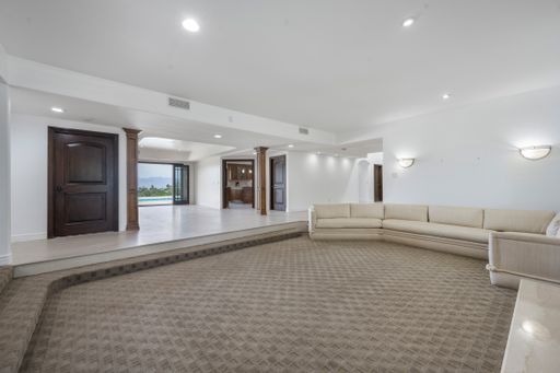 A spacious living room with curved sofa and flat screen TV in Encino, California