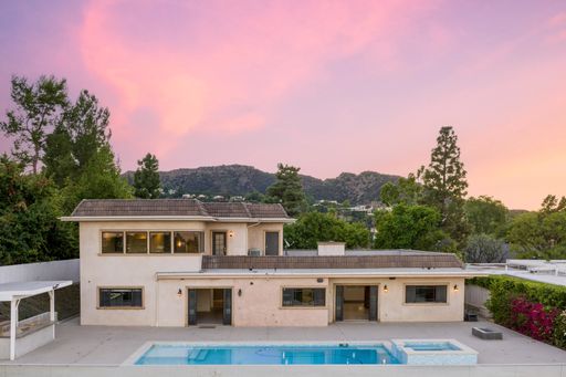 An aerial view of a house at sunset with a pool and covered patio in California