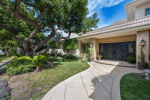 A luxury home with expansive green backyard, featuring lush trees in Encino, CA